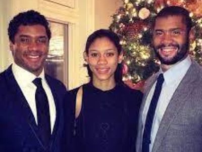 Russell, Anna, and Harrison, IV, Wilson are all wearing a formal attire as they pose in front of a Christmas tree.